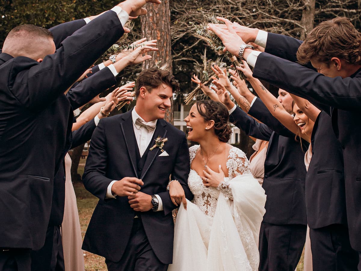 Wedding party makes an arch with their arms for the bride and groom at All 4 One Farms