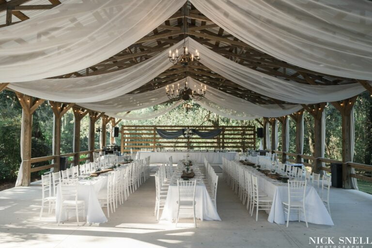 Wedding barn with banquet tables set with white linens and white Chiavari chairs at All 4 One Farms