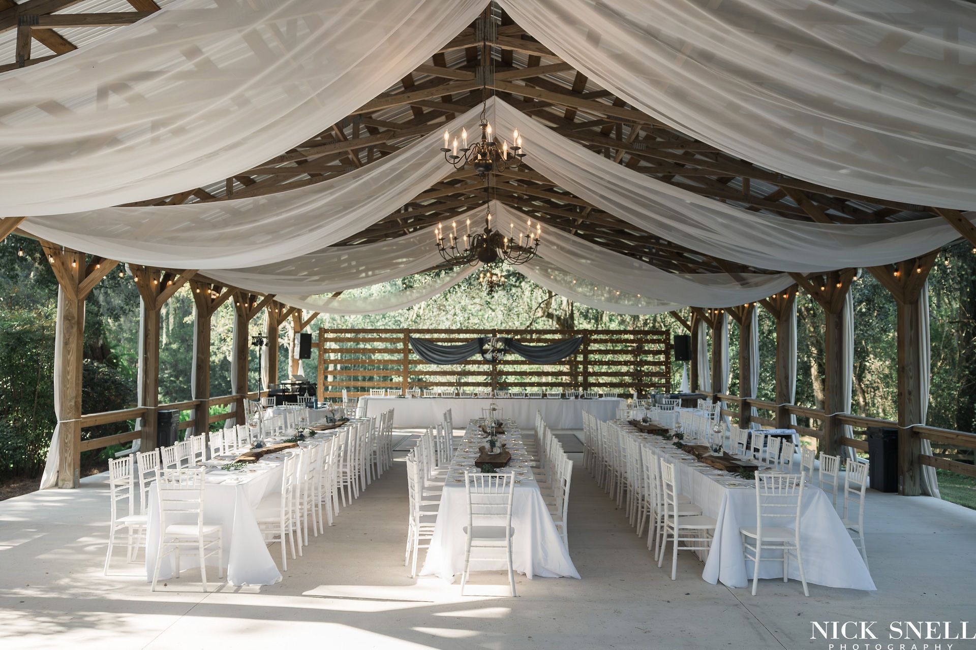 Wedding barn with banquet tables set with white linens and white Chiavari chairs at All 4 One Farms