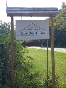 Roadside sign for All4One Farms along county road 218.