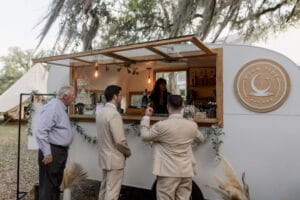 Groomsmen and guest wait outside mobile bar for their drinks at All4One Farms.